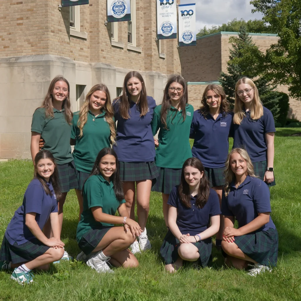 a group of students in uniform standing smiling in front of MSM