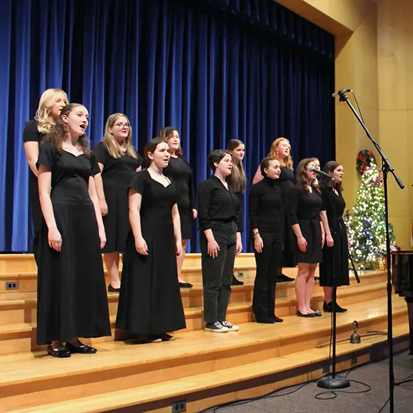 Girls singing at a holiday concert in black dresses