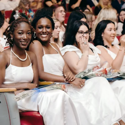 graduates of MSM dressed in white gowns sitting in the auditorium on graduation day