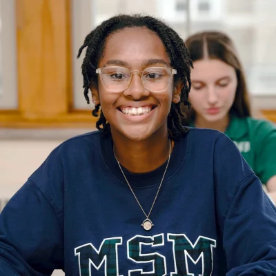 Girl smiling sitting in t a classroom at MSM