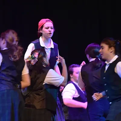 A group of girls singing and performing in the school musical